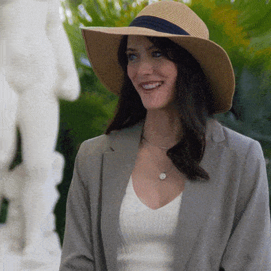 a woman wearing a hat and a gray jacket smiles