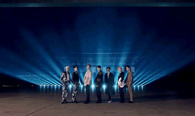 a group of men are standing in front of a large building lit up with lights