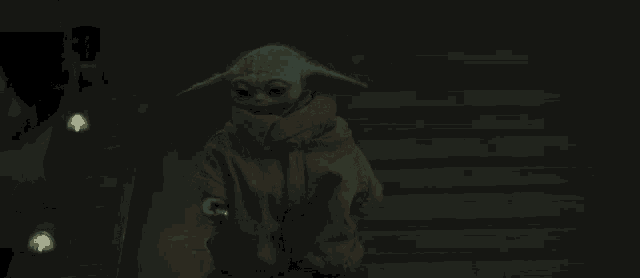 a baby yoda is walking down a set of stairs in a dark room .