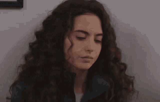 a woman with curly hair is looking at the camera with a serious look on her face