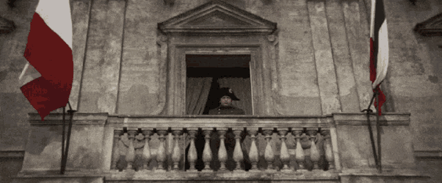 a man in a military uniform stands on a balcony