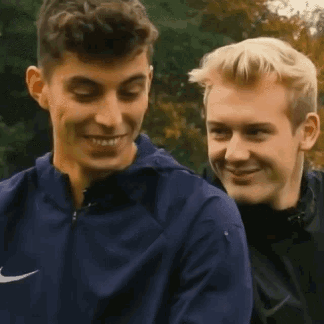 two young men are standing next to each other and smiling .