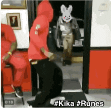 a man in a red hoodie is dancing in a room with a rabbit mask on his face .