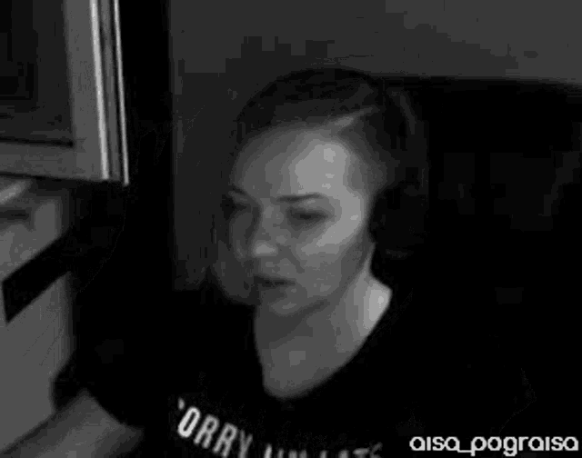 a black and white photo of a woman wearing headphones and a sorry i 'm late t-shirt .