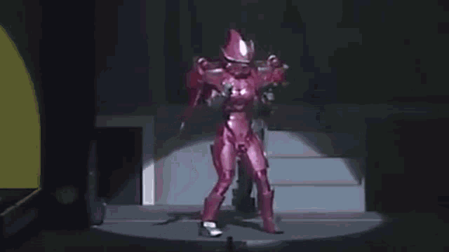 a person in a pink costume is standing on a stage with a gun .