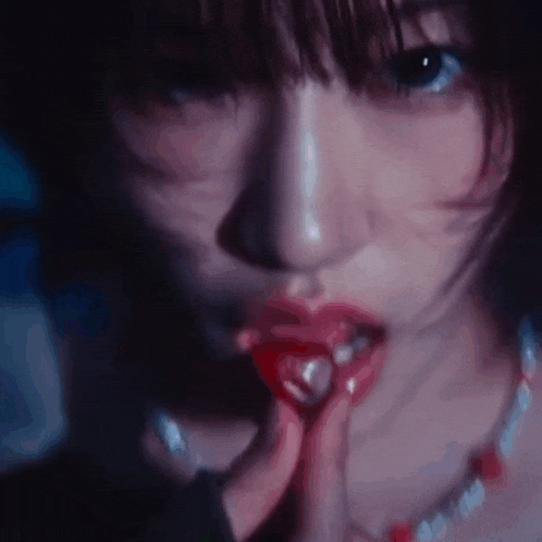 a close up of a woman 's face with red lips and a necklace .
