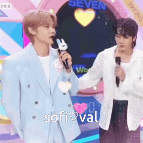 two men are standing next to each other on a stage and one of them is holding a microphone with a bunny on it .
