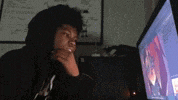 a man wearing a hoodie is looking at a computer screen .