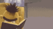 a stuffed animal is sitting in a chair reading a book .