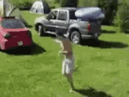 a man is jumping in the air in front of a truck with a kayak on top of it .