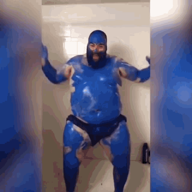 a man with a beard is covered in blue paint while standing in a shower .
