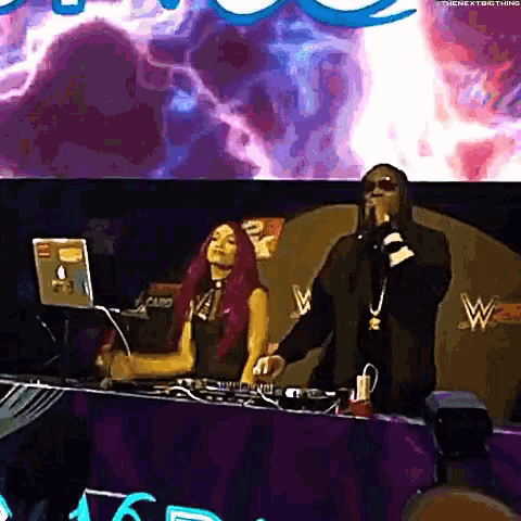 a man and a woman are dancing on a stage while a dj plays music .