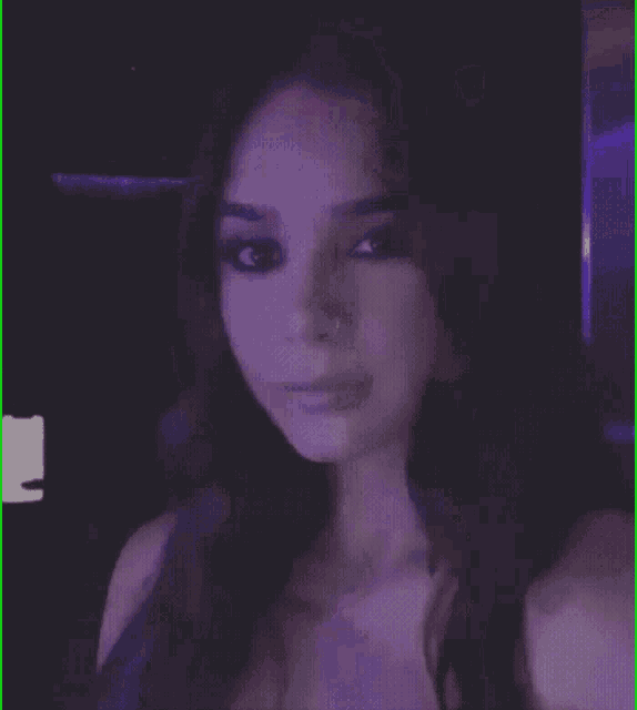 a close up of a woman 's face with purple light behind her