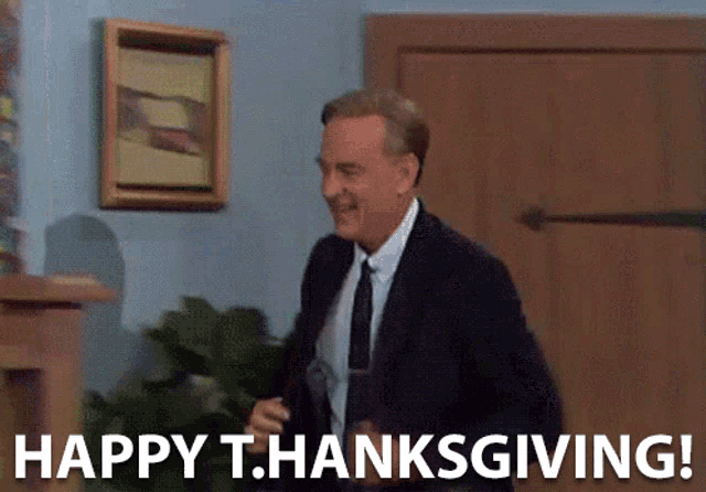 a man in a suit and tie is standing in front of a door and says happy thanksgiving
