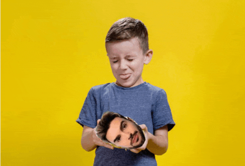 a young boy is holding a picture of a man 's face in his hands