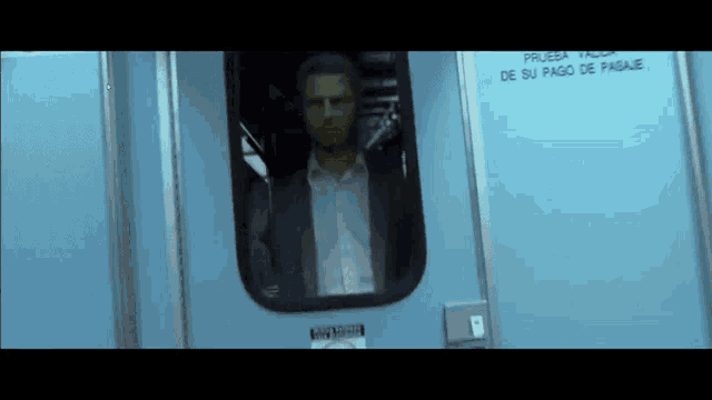 a man in a suit is looking out of a window with a sign that says prueba taxi
