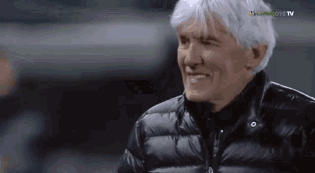 a man in a black jacket is smiling in front of a screen that says bwin