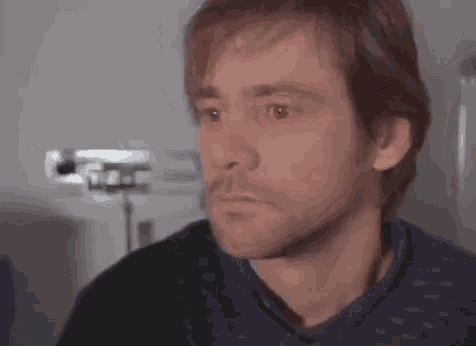 a close up of a man 's face with a beard and a serious look on his face .