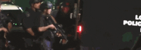 a group of police officers are walking down a street in front of a sign that says playback
