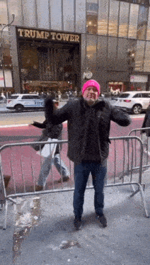 a man in a pink hat is standing in front of a trump tower