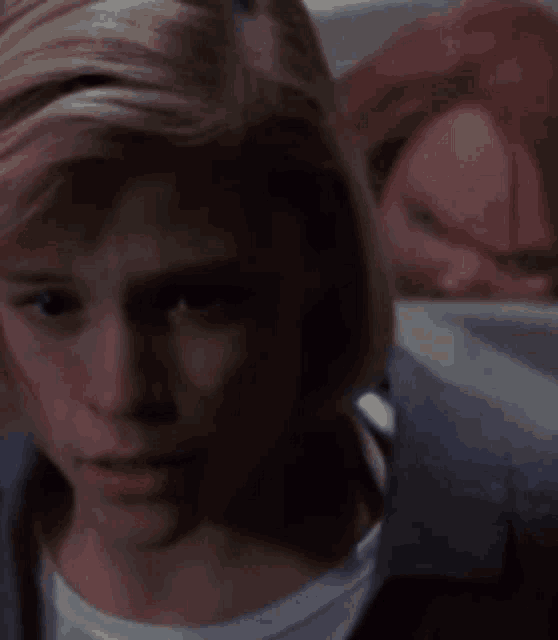 a close up of a person 's face with a man behind them