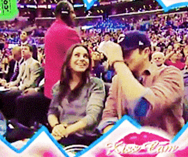 a picture of a man kissing a woman in a stadium with the words kiss cam on the bottom