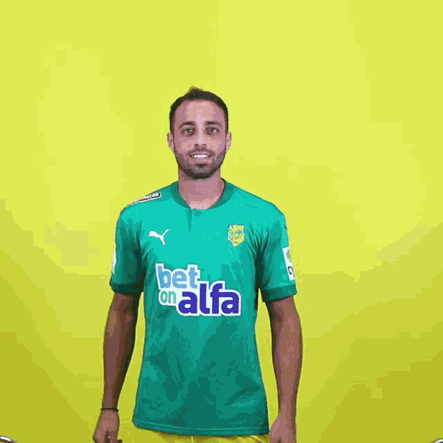 a man wearing a green shirt with bet on alfa on it