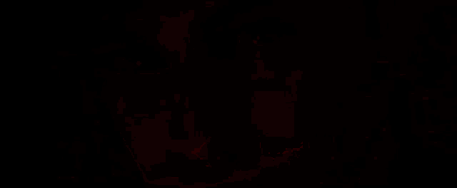 a close up of a man 's face in the dark with a red light shining on it .