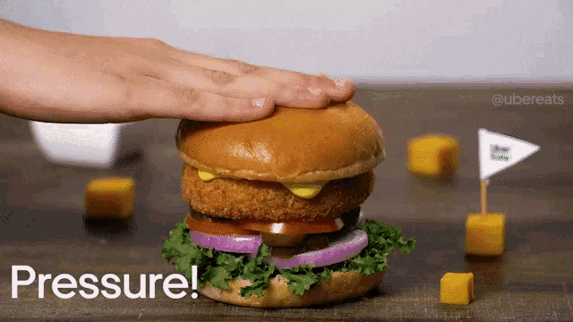 a person is pressing a hamburger with their hand and the word pressure is next to them