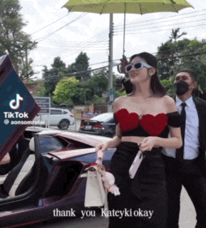 a woman holding an umbrella stands in front of a car with the caption thank you kateyki okay