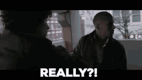 two men are standing next to each other in a dark room and one of them is saying `` really '' .