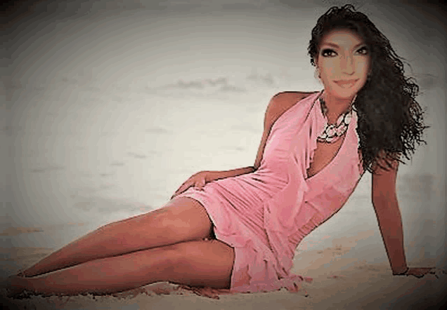 a woman in a pink dress and necklace is laying on the beach .