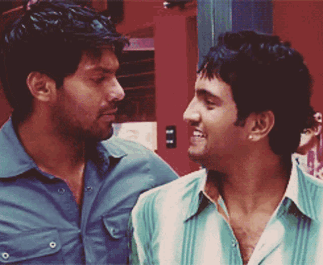 two men are looking at each other and one of them is wearing a green shirt