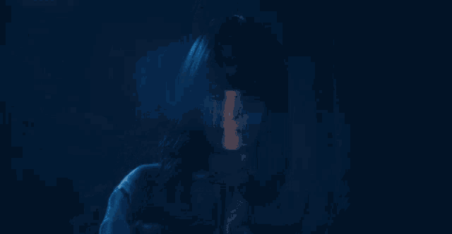 a close up of a woman 's face in the dark with a blue background .