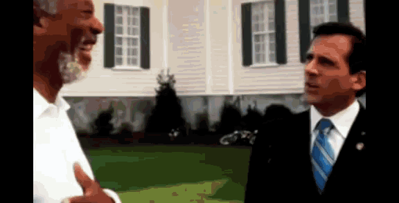 two men are standing in front of a house and talking to each other