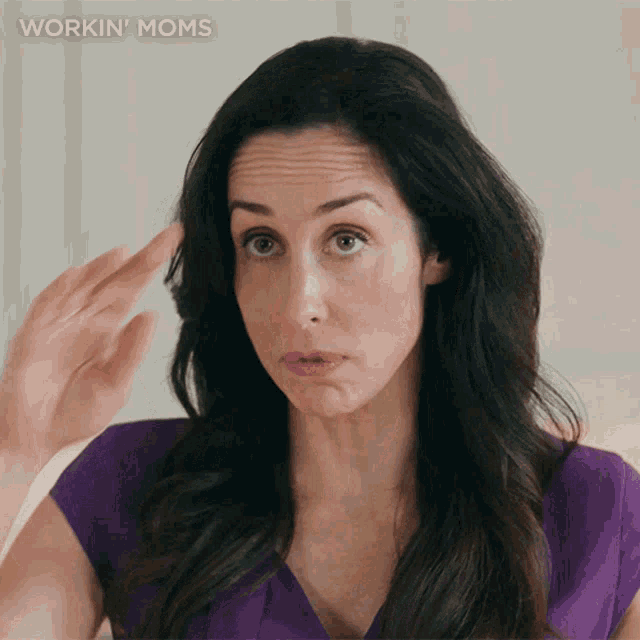 a woman in a purple shirt is making a funny face with the words workin ' moms above her
