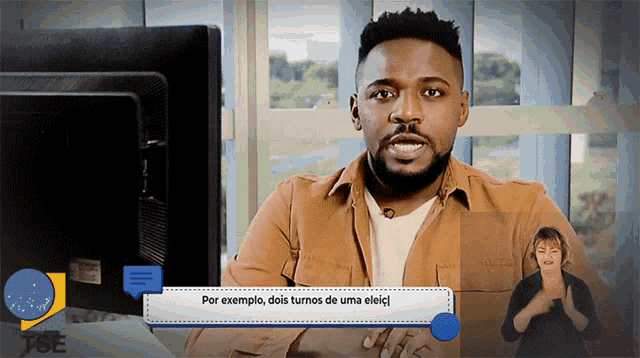 a man sitting in front of a computer screen with a sign that says por exemplo dois turnos de uma eleicj