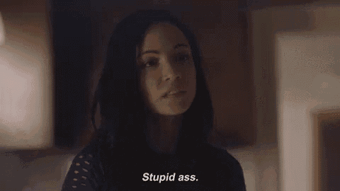 a woman is standing in a dark room talking to someone and says `` stupid ass '' .