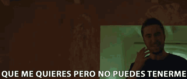 a man stands in a dark room with the words que me quieres pero no puedes tenerme written below him