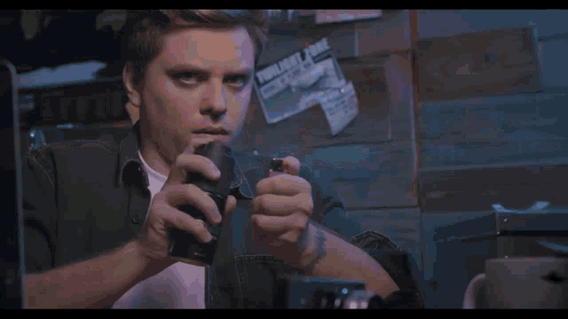 a man is lighting a lighter in front of a poster that says ' twinflame ' on it