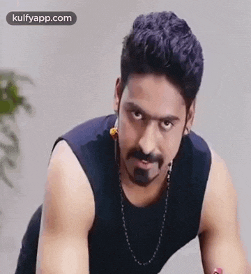 a man with a beard and a mustache is wearing a black tank top and a necklace .