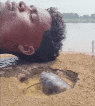 a man is laying in the sand with a fish in the sand
