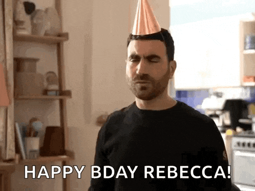 a man wearing a party hat is standing in a kitchen and saying happy bday rebecca .