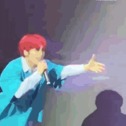 a man with red hair is singing into a microphone on stage