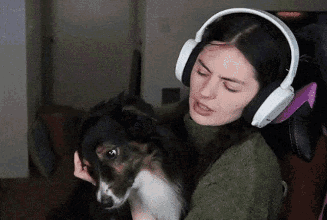 a woman wearing headphones holds a dog in her lap