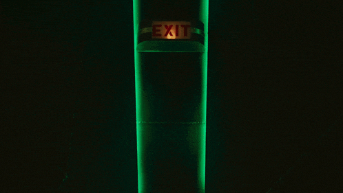 an exit sign is lit up on a green pole