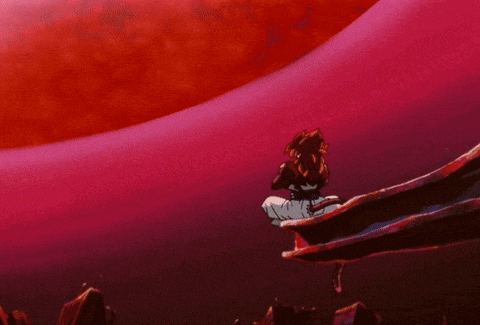 a person is sitting on a cliff looking at a large red object