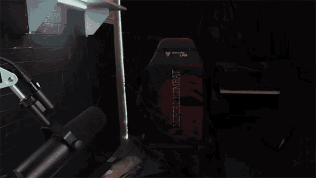 a man wearing glasses and a black hoodie sits in a gaming chair