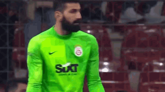 a soccer player with a beard is wearing a green shirt with the word sixt on it .