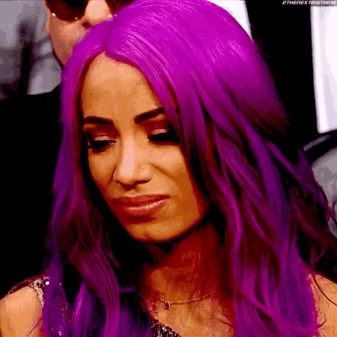 a woman with purple hair is making a sad face while standing next to a man .